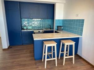 a blue kitchen with blue cabinets and two stools at Estrela Villas in Estrela