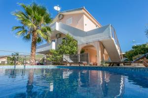 a house with a palm tree and a swimming pool at Family friendly apartments with a swimming pool Seget Vranjica, Trogir - 14409 in Donji Seget