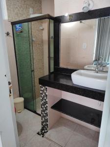 a bathroom with a sink and a glass shower at suites com piscina praia dos anjos in Arraial do Cabo