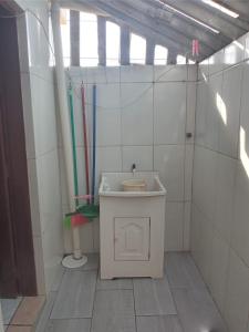 ein Bad mit einem Waschbecken in einem gefliesten Zimmer in der Unterkunft Kitnet in Tramandaí
