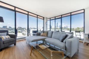 a living room with a couch and large windows at Aloft at Era with Sweeping Balcony Views in Melbourne