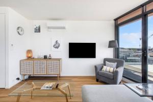 - un salon avec une télévision et une chaise dans l'établissement Aloft at Era with Sweeping Balcony Views, à Melbourne