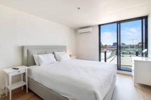a bedroom with a white bed and a large window at Aloft at Era with Sweeping Balcony Views in Melbourne