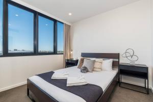 a bedroom with a large bed and large windows at Cityscape Serenity with Pool near Gabba and CBD in Brisbane