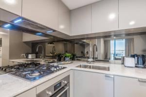 a kitchen with white cabinets and a stove top oven at Cityscape Serenity with Pool near Gabba and CBD in Brisbane