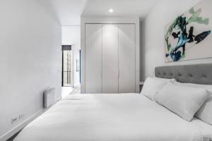 a white bedroom with a large bed with white sheets at Experience Elegance at a Resort-style Urban Oasis in Melbourne