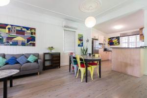 a living room with a couch and a table and chairs at Fernberg Cottage - Sunny Queenslander Charm in Brisbane