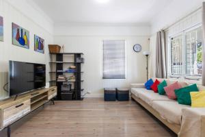 a living room with a couch and a television at Fernberg Cottage - Sunny Queenslander Charm in Brisbane