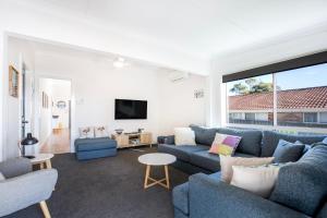 ein Wohnzimmer mit 2 blauen Sofas und einem TV in der Unterkunft Tillys Retreat I Pet Friendly I 3 Min Walk to Beach in Culburra Beach