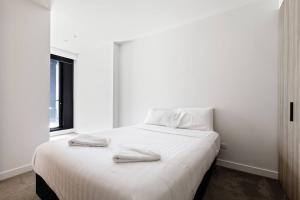 a white bed with two towels on top of it at The Claremont - Refined Resort Style Living in Melbourne