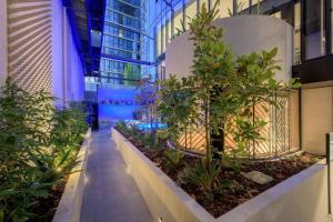 a walkway in a building with trees and plants at The Claremont - Refined Resort Style Living in Melbourne