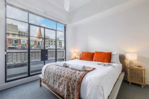 a bedroom with a bed and a large window at Majorca Classic - Boutique Flinders Lane Balcony Pad in Melbourne