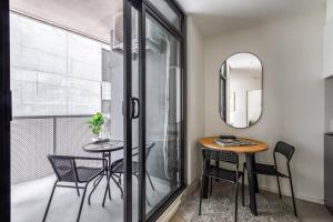 a dining room with a table and chairs and a mirror at Little Lonsdale Loft - Primely Located in the CBD in Melbourne