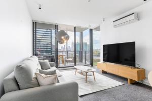 sala de estar con sofá y TV de pantalla plana en Skyhigh's Edge - City View Serenity by St Kilda Rd, en Melbourne