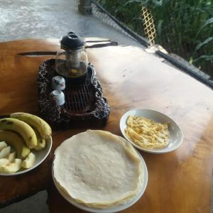 a table with plates of food and bananas on it at Tee Homestay hmong and trekking in Lao Cai