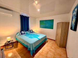 a bedroom with a bed with a blue bedspread at Tahiti - Kea Lodge in Papara