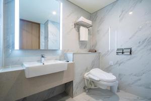 a bathroom with a sink and a toilet and a mirror at Centum Business Hotel in Busan