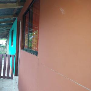 een rode muur met een raam aan de zijkant van een huis bij Departamento Minae in Puerto Jiménez