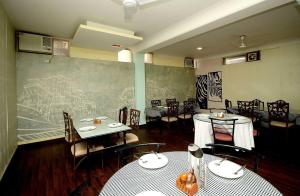 un comedor con mesas y sillas y una pizarra en Collection O 8704 Hotel Sakshi, en Gurgaon