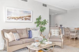 un soggiorno con un divano, un tavolo e delle sedie di Hamptons-inspired Waterfront Living on Moana Beach a Adelaide