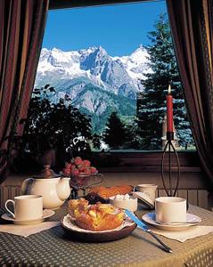 una mesa con comida y vistas a la montaña en Hotel Dei Camosci, en Courmayeur