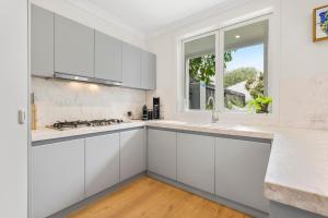 a kitchen with white cabinets and a window at Chic Urban Oasis in Richmond in Melbourne
