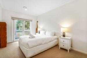 a white bedroom with a bed and a window at Chic Urban Oasis in Richmond in Melbourne