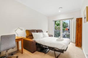 a living room with a bed and a desk and a window at Chic Urban Oasis in Richmond in Melbourne