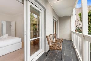 a porch with two chairs and a bed on a balcony at Chic Urban Oasis in Richmond in Melbourne