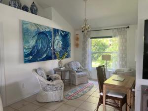 sala de estar con sillas, mesa y una pintura en Seagrape retreat, en Sebastian