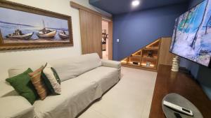 ein Wohnzimmer mit einer weißen Couch und einem Gemälde an der Wand in der Unterkunft Confortável Casa de Praia em Itacimirim - 04 SUÍTES in Itacimirim
