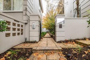 an alleyway between two buildings with leaves on the ground at 'The Courtyard Chateau' Fresh and Modern off Toorak Rd in Melbourne