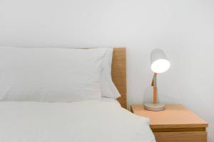 a bed with white sheets and a lamp on a nightstand at 'BOWIE' Sun soaked Comfort in the Heart of Richmond in Melbourne