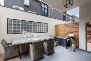 een patio met een tafel en stoelen en een grill bij Elster's Edge - A Stylish Elwood Escape with Terrace in Melbourne