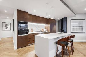 a kitchen with a white counter and wooden cabinets at Top of Town - Penthouse with Every Opulence in Melbourne