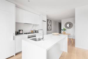 a white kitchen with a sink and a counter at Executive Resort-Style Living at Leafy Albert Park in Melbourne