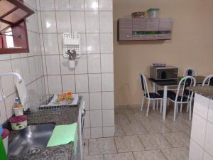 een keuken met een wastafel en een tafel met stoelen bij Casa de Praia completa em Cabo Frio 6 para até 5 pessoas in Cabo Frio