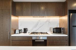 a kitchen with a stove and a microwave at Lakeside Five Star Luxury with Uninterrupted Views in Melbourne