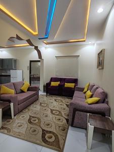 a living room with purple couches and yellow pillows at شاليهات ستي لاند in Taif