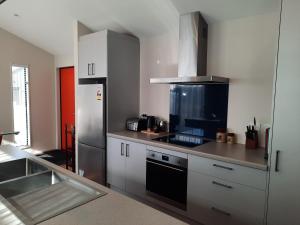 uma cozinha com armários brancos e um forno com placa de fogão em Colour on Cairnmuir em Wanaka