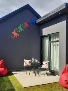 een huis met een tafel en stoelen ervoor bij Colour on Cairnmuir in Wanaka