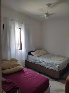 um quarto com 2 camas e uma janela em Cantinho da Lu em apt inteiro 800 mt da praia em Bertioga
