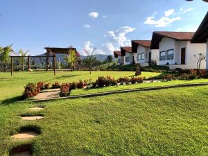 einen Rasenplatz mit einem Haus und einem Garten in der Unterkunft Pousada Pé da Serra in Capitólio