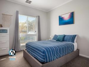 1 dormitorio con 1 cama con edredón azul y ventana en 3BR Contemporary Home with Sea Views, en Victor Harbor