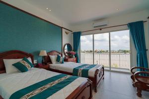 a bedroom with two beds and a large window at CHUONG DUONG HOTEL in Mỹ Tho