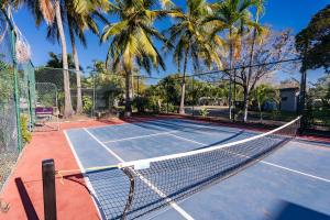 a tennis court with a net and palm trees at BIG4 Tasman Holiday Parks - Rowes Bay in Townsville