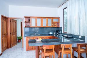 una cocina con armarios de madera y una barra con sillas en EXCLUSIVE CONDO GALAPAGOS & BEYOND 2 en Puerto Ayora