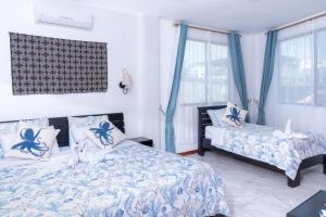 a bedroom with two beds and blue curtains at EXCLUSIVE CONDO GALAPAGOS & BEYOND 2 in Puerto Ayora