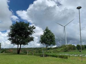 un molino de viento y un árbol en un campo con en ศรีวิภา​ฮิลล์​แคมป์ปิ้ง, en Ban Thung Samo