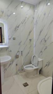 a white bathroom with a toilet and a sink at شاليهات ستي لاند in Taif